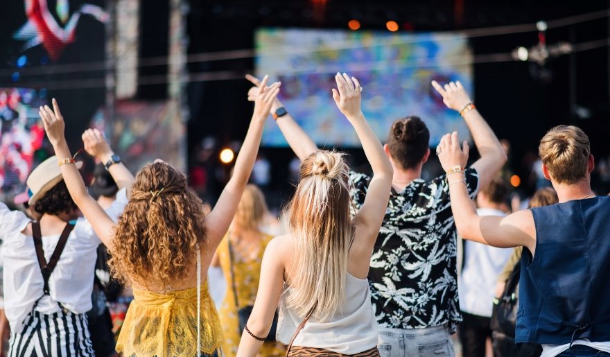 A lively group of festival-goers at Myrtle Beach, hands raised in excitement, enjoying summer music and festivities.
