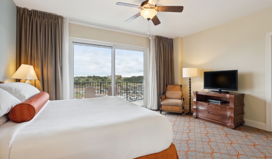 A cozy hotel room featuring a large bed and a flat-screen TV, promoting winter stays at Marina Inn, Myrtle Beach.