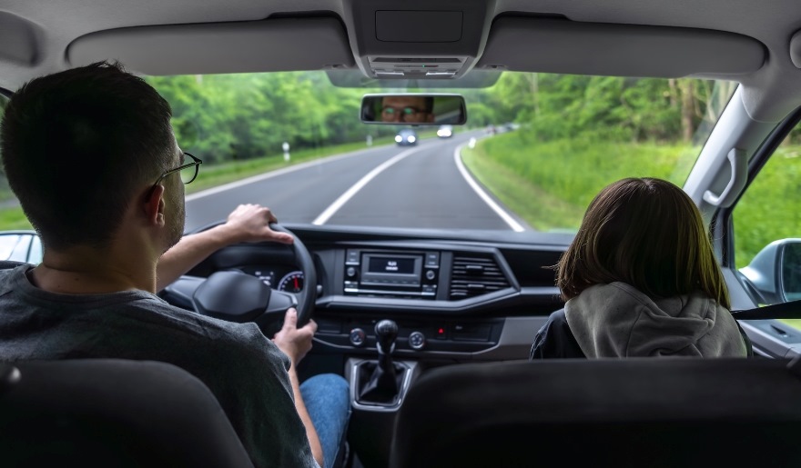 View from inside a car showing travelers driving along a tree-lined highway, representing road trips as a cost-effective way to reach Myrtle Beach compared to flying, especially for families and groups.