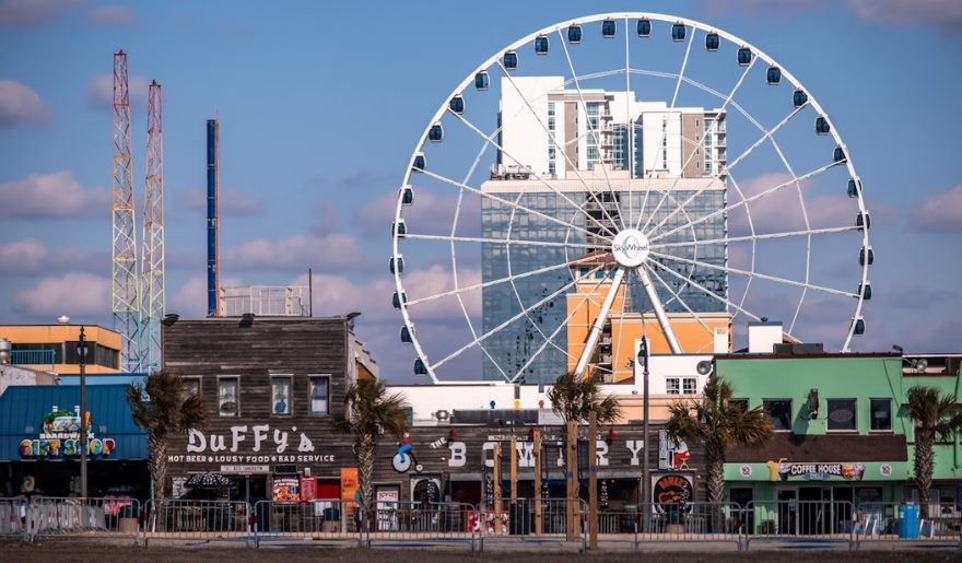 The Myrtle Beach SkyWheel building is visible behind a vibrant Ferris wheel, perfect for Myrtle Beach Attractions for Kids