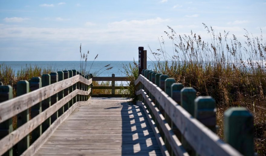 A wooden boardwalk stretches toward the ocean at Myrtle Beach State Park, ideal for family outings and exploration.