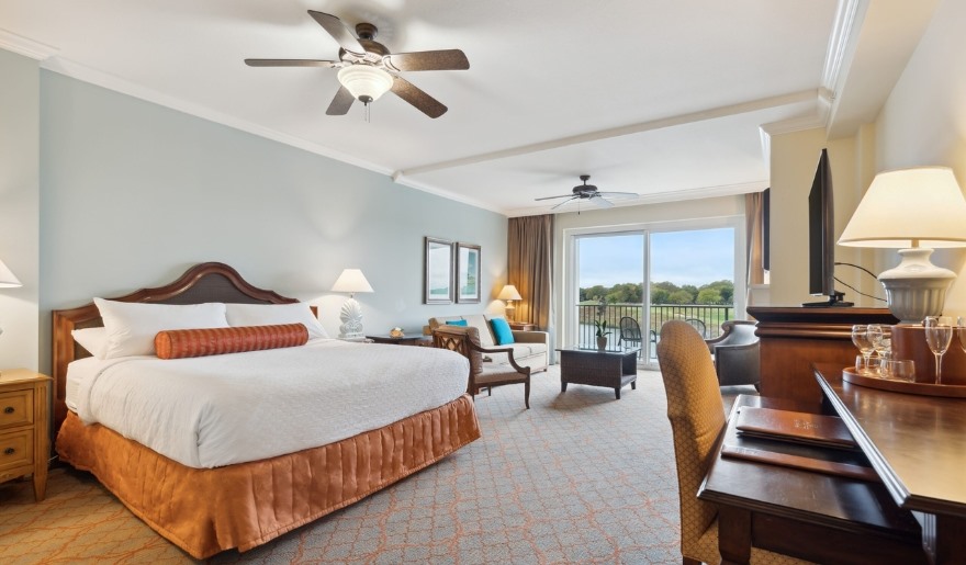 A luxurious hotel room featuring a king bed, television, and a balcony at Marina Inn, perfect for a Myrtle Beach bachelorette party.