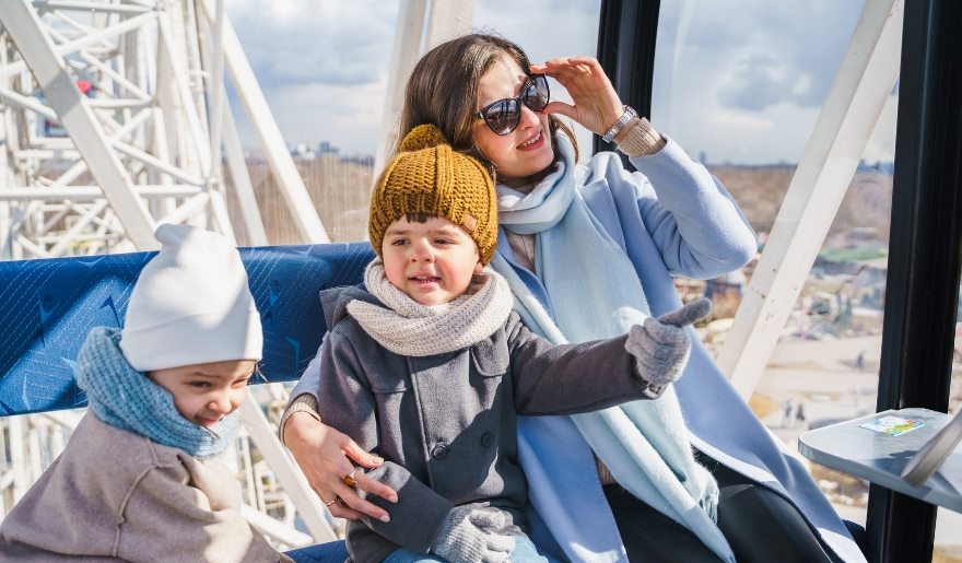 A woman and her two children smile as they ride the SkyWheel at Myrtle Beach, with scenic views in the background.