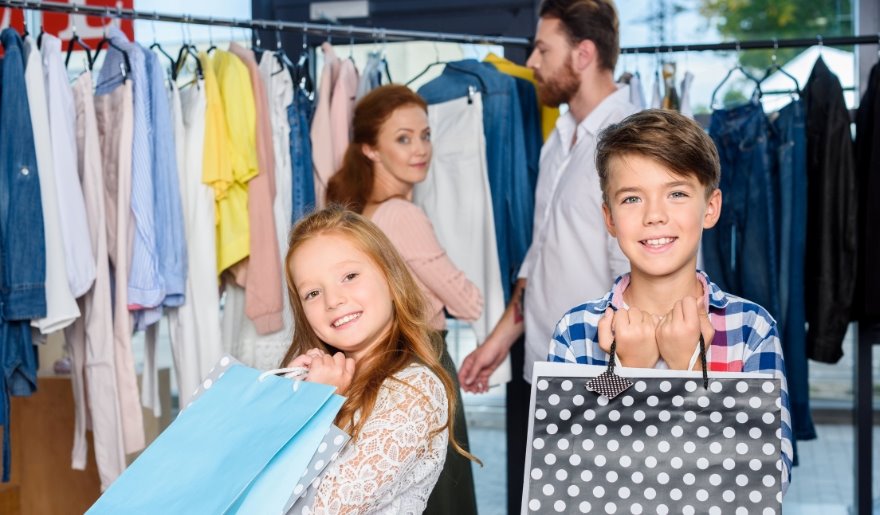 A family poses with shopping bags in a clothing store at The Market Common, Myrtle Beach, smiling and enjoying their day.