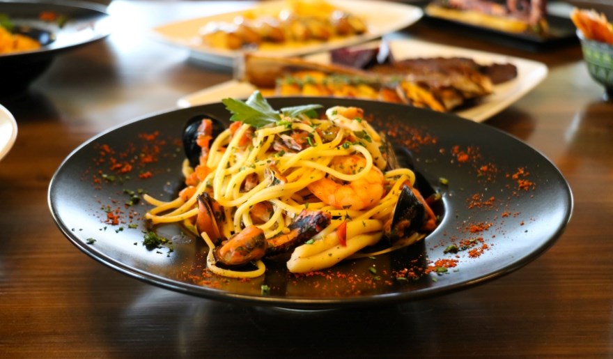 A table filled with various pasta dishes and sides, showcasing a feast at Hook & Barrel in Myrtle Beach for large groups.