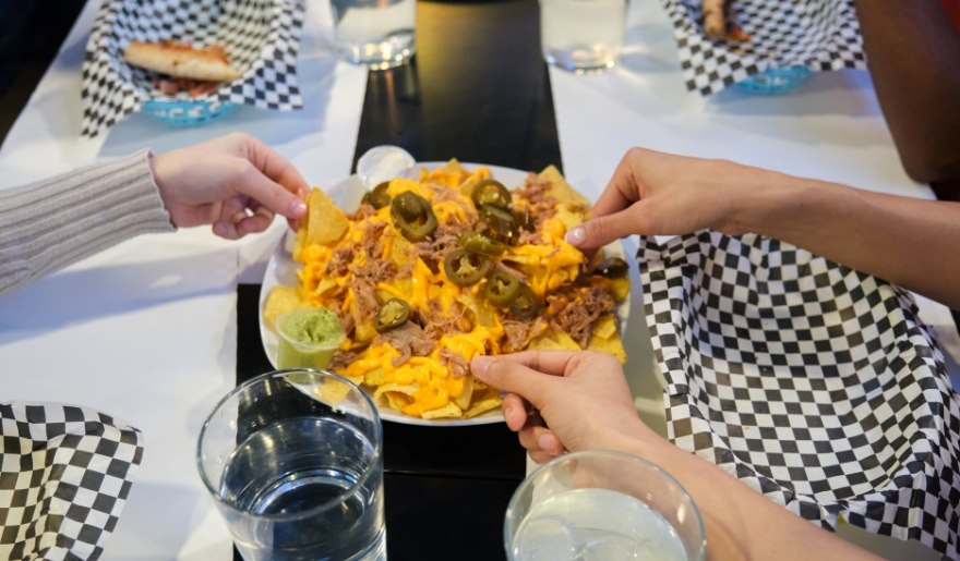 A group of friends enjoying nachos together at a table in Nacho Hippo Cantina Maximo, Myrtle Beach.