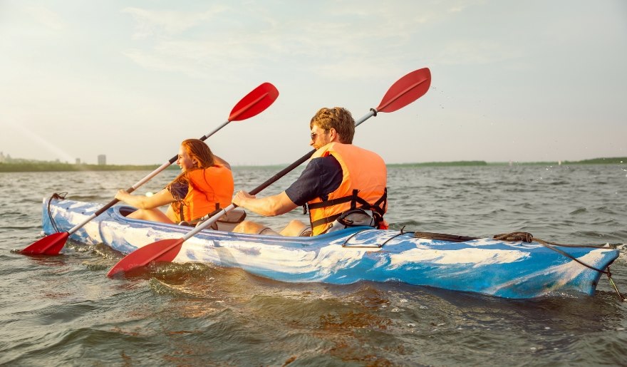 A kayak with two individuals paddling on the water at Myrtle Beach during April's beach activities.