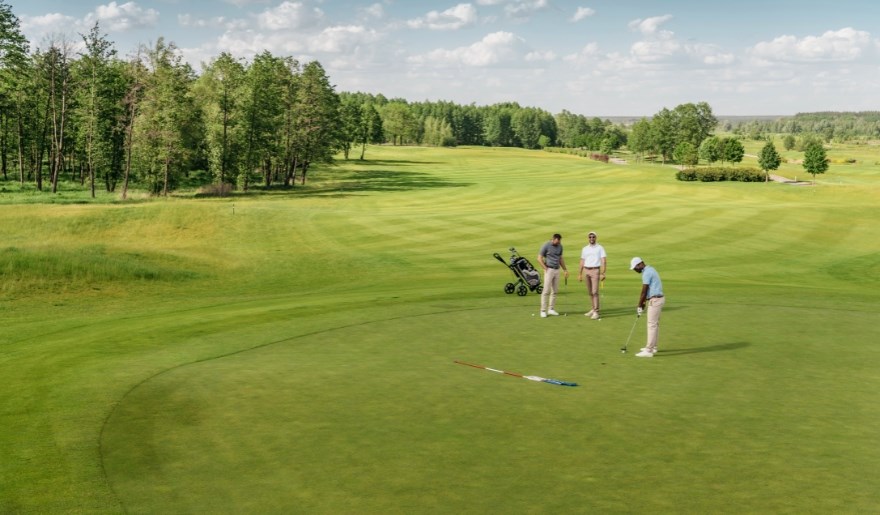 Three individuals engaged in a game of golf on a vibrant green field at Myrtle Beach in February.