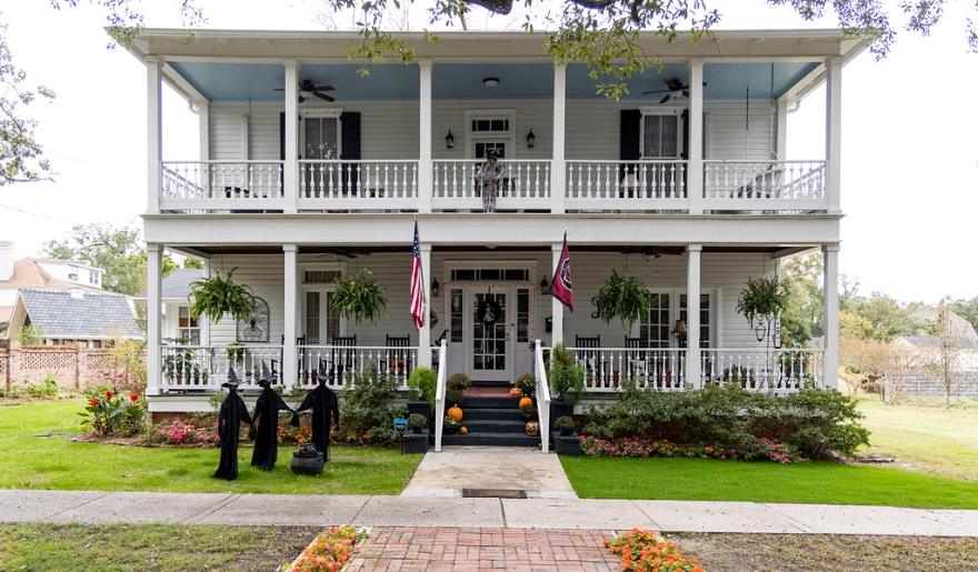 A charming white house with a porch and an American flag, featured in Myrtle Beach activities for couples in Georgetown.