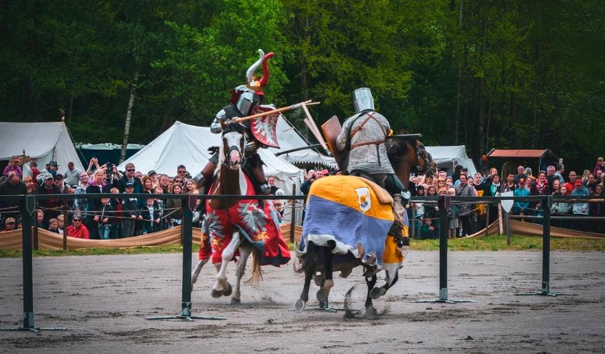 Two armored knights on horses engage in combat during a medieval battle at Medieval Times in Myrtle Beach.