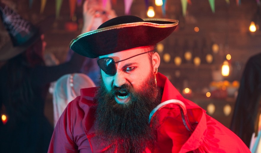 A man dressed as a pirate, featuring a beard and eye patch, promoting a family-friendly pirate show in Myrtle Beach.