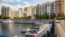 Jet skis lined up at a resort dock with a multi-story hotel complex in the background.