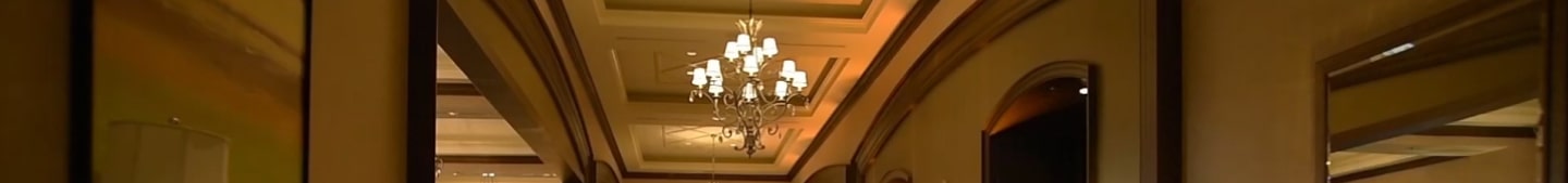 An elegant hallway with a large, warm chandelier hanging from a recessed ceiling