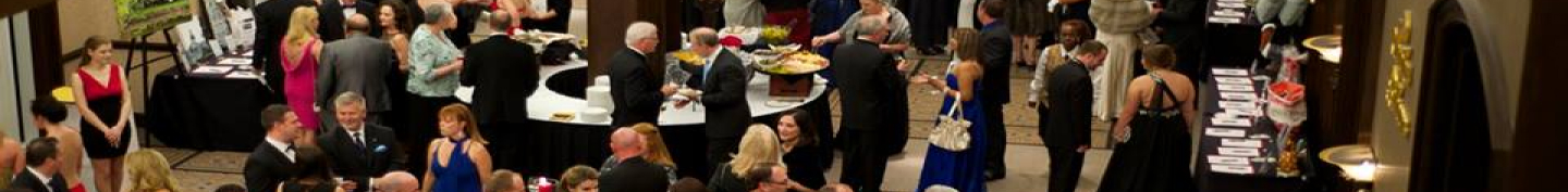 A crowded, formal cocktail reception with guests mingling near food stations.