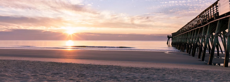 Serene beach sunrise over the ocean and pier during the peaceful Myrtle Beach Off-Season