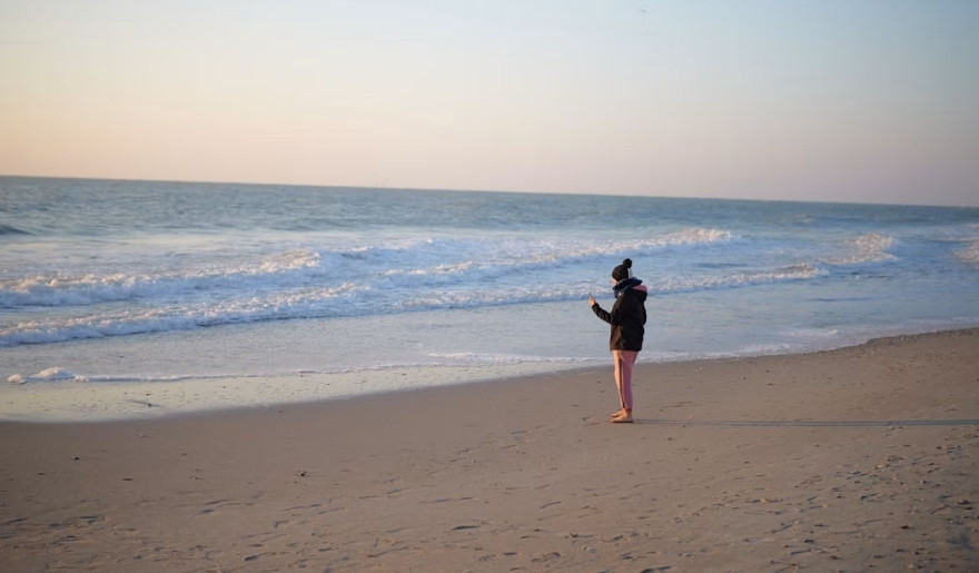 Person enjoying a quiet winter walk along the Myrtle Beach shoreline beside rolling ocean waves.