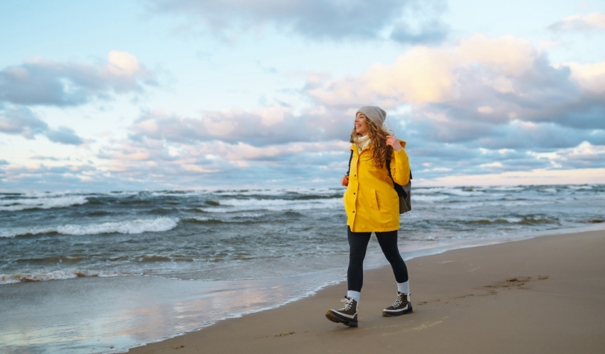 Woman in a yellow raincoat enjoying a winter walk along the Myrtle Beach shoreline.